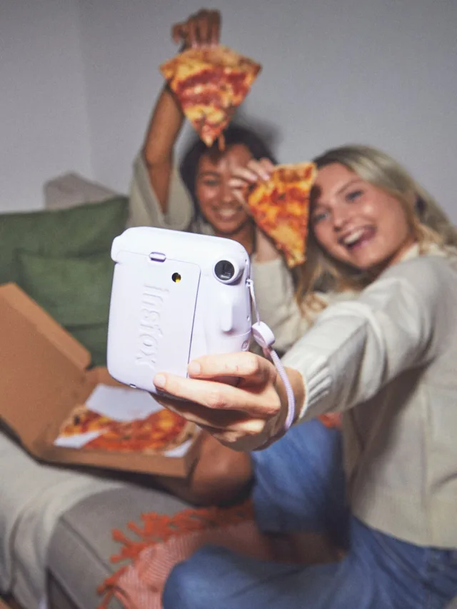 duas meninas comendo pizza e tirando fotos com câmera Instax Mini 11